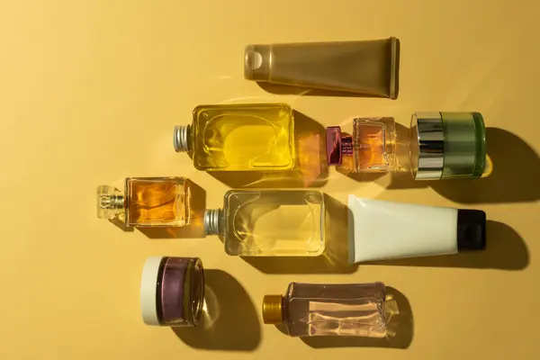 Flat lay of beauty products bottles, tub and tube with copy space on yellow background. Health and beauty, beauty product, make up and colour concept.