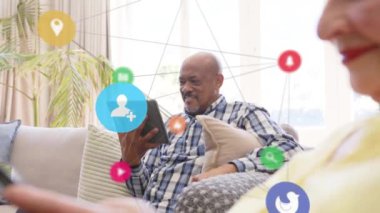 Tablet kullanan yaşlı Afro-Amerikan bir adam üzerindeki ikonlarla olan bağlantıların animasyonu. Küresel ağlar, bağlantılar, hesaplama ve veri işleme kavramı dijital olarak oluşturulmuş video.