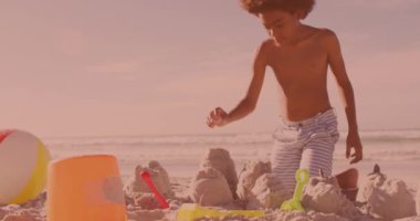 Afrika kökenli Amerikalı genç çocuk kumsalda kumdan kaleler inşa ediyor. Çocukluk, seyahat ve tatil konsepti