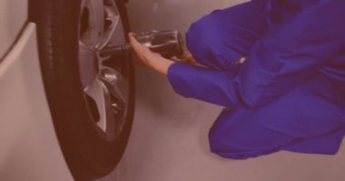 Beyaz kadın tamirci tamir istasyonunda pnömatik ingiliz anahtarıyla bir arabanın vida tekerleği. Araba tamir hizmeti kavramı