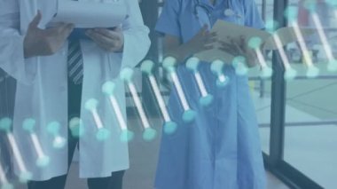 Hastanede rapor okuyan erkek ve kadın doktorların üzerinde dönen DNA yapısının animasyonu. Tıbbi sağlık ve araştırma teknolojisi kavramı