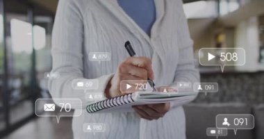 Sosyal medya simgelerinin beyaz yaşlı bir kadına karşı yüzerek evde not alması. Sosyal medya ağı ve emeklilik yaşam tarzı kavramı