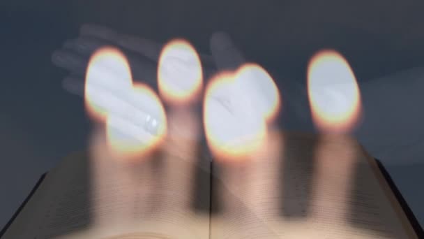 女性の手の上にろうそくを燃やす複合ビデオは オープン聖書に対するローズマリーの祈りで キリスト教と宗教の概念 — ストック動画