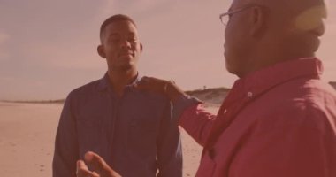 Afrikalı Amerikalı bir adam sahilde oğluyla konuşuyor. Babalık, aşk ve tatil kavramı