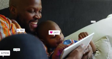 Afro-Amerikan baba ve oğlunun dijital tabletten video izlemesi üzerine bilgilendirme barlarının animasyonu. Dijital bileşim, çoklu pozlama, çocukluk, birliktelik, sosyal medya anımsatıcı, teknoloji.