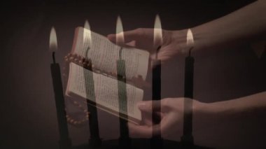 İncil 'i ve tespih duasını tutan kadınların eline karşı yanan mumların birleşik videosu. Hıristiyanlık ve din kavramı
