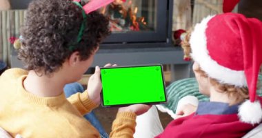 Kafkasyalı iki erkek arkadaş yeşil ekranlı, ağır çekimde noel tableti görüntülü görüşme yapıyorlar. İletişim, aile, arkadaşlar, Noel, kutlama, birliktelik, gelenek ve yaşam tarzı, değiştirilmemiş.