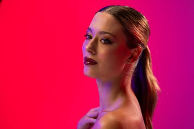 Beyaz kadın pembe arka planda kırmızı ruj ve mavi tırnak cilası kullanıyor. Kozmetik, makyaj, kadın modası ve güzelliği, değiştirilmemiş.