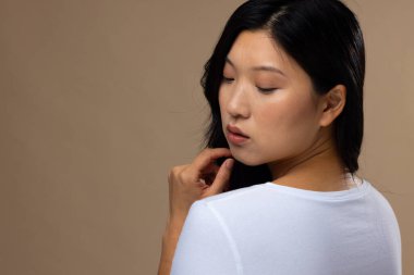 Bej arka planda doğal makyaj ve beyaz tişört giyen Asyalı kadın, fotokopi alanı. Kozmetik, makyaj, kadın modası ve güzelliği, değiştirilmemiş.