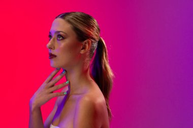 Beyaz kadın mor arka planda kırmızı ruj ve mavi tırnak cilası kullanıyor. Kozmetik, makyaj, kadın modası ve güzelliği, değiştirilmemiş.