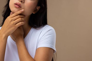 Bej arka planda doğal makyaj ve beyaz tişört giyen Asyalı kadın, fotokopi alanı. Kozmetik, makyaj, kadın modası ve güzelliği, değiştirilmemiş.