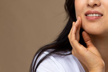 Bej arka planda doğal makyaj ve beyaz tişört giyen Asyalı kadın, fotokopi alanı. Kozmetik, makyaj, kadın modası ve güzelliği, değiştirilmemiş.