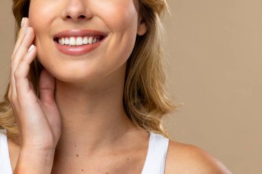 Beyaz kadın doğal makyaj yapıyor ve bej arka planda bej oje sürüyor. Kozmetik, makyaj, kadın modası ve güzelliği, değiştirilmemiş.