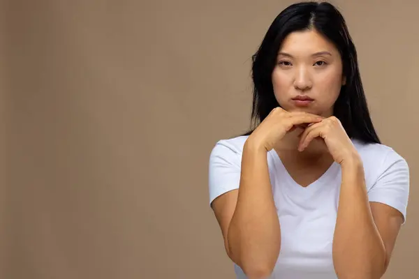 Portrait of asian woman wearing natural makeup and white t-shirt on beige background, copy space. Cosmetics, makeup, female fashion and beauty, unaltered.
