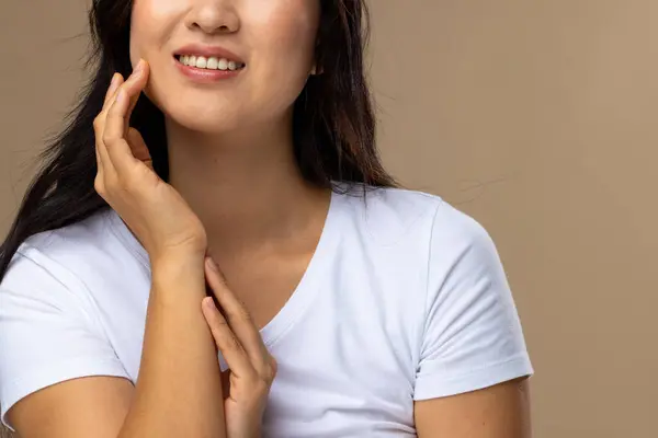 Asian woman wearing natural makeup and white t-shirt on beige background. Cosmetics, makeup, female fashion and beauty, unaltered.