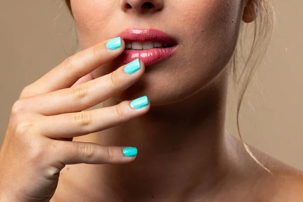 Caucasian woman wearing natural makeup and blue nail polish on beige background. Cosmetics, makeup, female fashion and beauty, unaltered.
