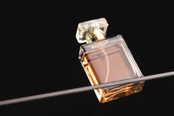 Beauty product perfume bottle on glass shelf, copy space on black background. Health and beauty, make up and beauty concept.