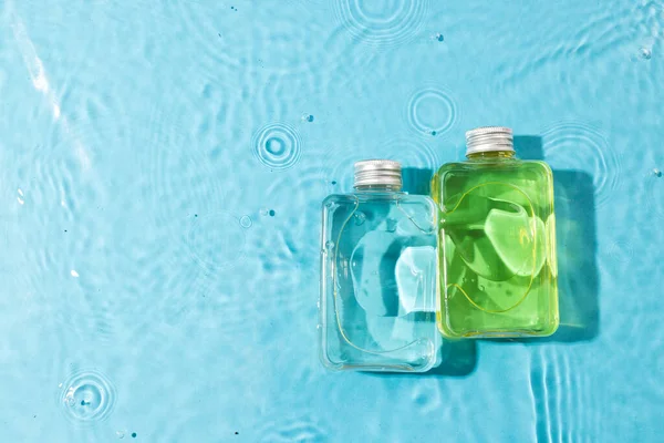 Beauty product bottles in water with copy space background on blue background. Health and beauty, make up and beauty concept.