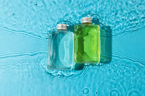 Beauty product bottles in water with copy space background on blue background. Health and beauty, make up and beauty concept.