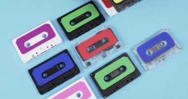 Afro-Amerikan bir adamın mavi arka planda fotokopi alanı olan retro kasetleri düzenlerken çekilmiş bir video. Retro, nostalji, vintage, müzik ve bant kayıt kavramı.