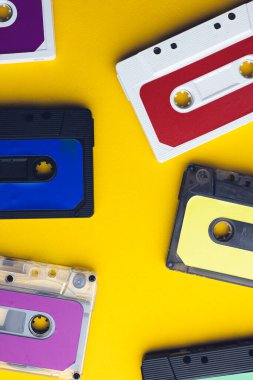 Sarı arka planda altı renkli kaset görüntüsü. Müzik, ses, dinleme, eğlence ve nostalji konsepti.