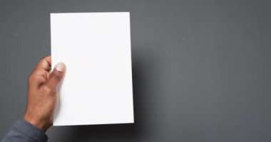 Elinde boş sayfası olan Afrikalı Amerikalı bir adamın gri arka planda kopyası olan bir kitabın videosu. Kitap, edebiyat, kağıt, yazı, doku ve materyal kavramı.