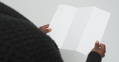 Elinde boş bir sayfa tutan Afro-Amerikan bir adamın beyaz arka planda kopyalama alanı olan videosu. Kitap, edebiyat, kağıt, yazı, doku ve materyal kavramı.