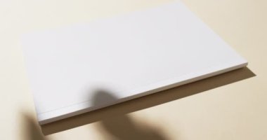 Beyaz boş sayfaları olan bir kitap videosu ve sarı arkaplanda gölgeler. Kitap, edebiyat, kağıt, yazı, doku ve materyal kavramı.