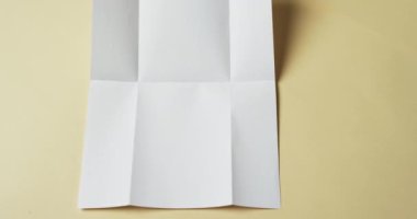 Sarı arka planda kırışıklıkları olan beyaz kağıt parçası videosu. Kağıt, yazı, doku ve malzeme konsepti, kopyalama alanı.