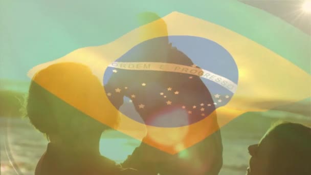 晴れたビーチで幸せな白人の両親と子供の上のブラジルの旗のアニメーション ブラジル 子供時代 愛国心 デジタル生成されたビデオ — ストック動画