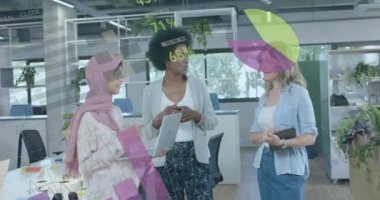 Animation of financial data processing over diverse businesswomen in office. Global business, finance, computing and data processing concept digitally generated video.