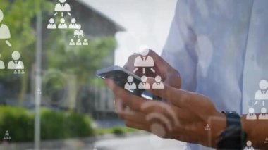 Çift ırklı adamın orta kesiminde akıllı telefondan kayan akış çizelgeleri ve simgelerin animasyonu. Dijital bileşik, çoklu pozlama, iş, iletişim, kablosuz ve teknoloji kavramı.