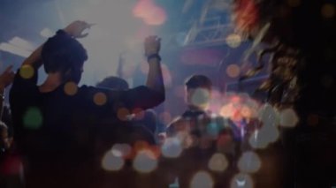 Konser sırasında ışık noktaları ve şehir manzarası üzerinde dans eden ve el kaldıran mutlu insanlar. Parti, müzik ve kutlama, değiştirilmemiş.