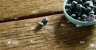 Sosyal medya simgelerinin ahşap masadaki bir kasede böğürtlen kapaklarına karşı yüzen animasyonları. Sosyal medya ağı ve yemek restoranı kavramı