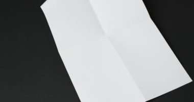 Siyah arka planda kırışıklıkları olan beyaz kağıt parçasının videosu. Kağıt, yazı, doku ve malzeme konsepti, kopyalama alanı.