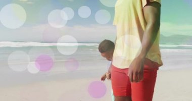 Mutlu Afro-Amerikan baba ve oğlunun kumsalda yürümesi üzerine ışık noktalarının animasyonu. Babalık, çocukluk, tatiller, aile ve boş zaman, dijital olarak oluşturulmuş video.