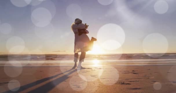 在喜庆的非洲裔美国新郎在夕阳西下的海滩上举起新娘身上的亮点动画 假期和婚姻 数码视频 — 图库视频影像