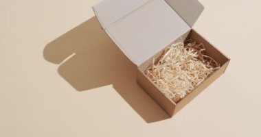 Paketleme malzemeleriyle dolu açık bir karton kutu sade bir arka planda, kopya alanı ile sunuluyor. Basitliği nakliye, ambalaj ve boks deneyimlerinin temaları.