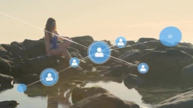 Kumsaldaki mutlu beyaz kadın üzerinde daireler çizerek bağlı ikonlar ağının animasyonu. Bağlantı, iletişim, hesaplama, doğa ve ifade konsepti dijital olarak oluşturulmuş video.
