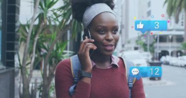 Akıllı telefon kullanan Afrikalı Amerikalı kadınların sosyal medya simgelerinin ve verilerinin animasyonu. Küresel finans, iş, bağlantılar, hesaplama ve veri işleme kavramı dijital olarak oluşturulmuş video.