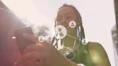 Akıllı telefon kullanan iki ırklı kadının üzerindeki simgelerle bağlantı ağının animasyonu. Küresel seyahat, tatil, bağlantılar, hesaplama ve veri işleme kavramı dijital olarak oluşturulmuş video.