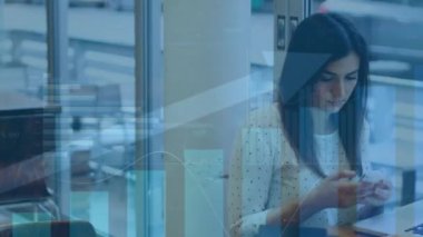 Kafedeki akıllı telefon ve dizüstü bilgisayar kullanan beyaz bir kadının grafiklerde veri işleme animasyonu. Ağ, veri, iş, uzaktan çalışma, dijital arayüz ve iletişim, dijital olarak oluşturulmuş video.