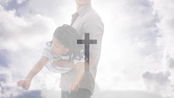 十字架の十字架のクロスモニュメントと 息子と遊ぶ聖職者の父上に曇った空のアニメーション キリスト教 子供時代 ライフスタイル デジタル生成されたビデオ — ストック動画