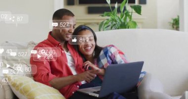 Kanepede dizüstü bilgisayarla kucaklaşan Afro-Amerikan çiftin sosyal medya bildirimleri. İlişki, ağ, dijital arayüz, yaşam tarzı ve iletişim, dijital olarak oluşturulmuş video.