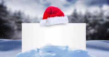 Beyaz kartın üzerine düşen kar animasyonu. Fotokopi alanı ve kış manzarasında Noel Baba şapkası. Noel, şenlik, kutlama ve gelenek konsepti dijital olarak oluşturuldu.