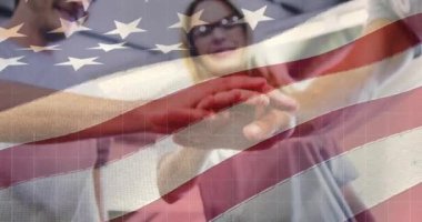 Amerikan bayrağının mutlu beyaz erkek ve kadın arkadaşlarının el ele tutuşması üzerine animasyonu. Amerika, kutlama, takım çalışması, arkadaşlık, yaşam tarzı ve vatanseverlik, dijital olarak üretilen video.
