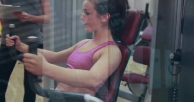 Beyaz bir kadının spor salonunda kadın antrenörle egzersiz yapması üzerine finansal veri işleme animasyonu. Spor, aktif yaşam tarzı, finans ve dijital arayüz konsepti dijital olarak oluşturulmuş video.