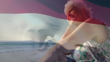 Sahildeki Kafkasyalı yaşlı kadın için Hollanda bayrağı animasyonu. Vatanseverlik, bayraklar ve yaşam tarzı konsepti dijital olarak oluşturulmuş video.
