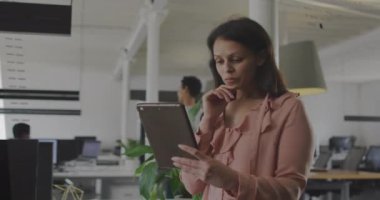Ofiste tablet kullanan melez iş kadınının veri işleme animasyonu. İş, iletişim, teknoloji, bilgisayar ve dijital arayüz kavramı dijital olarak oluşturulmuş video.