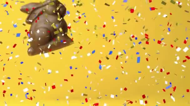 Анимация Конфетти Над Шоколадным Кроликом Желтом Фоне Пасху Пасха Традиции — стоковое видео